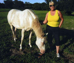 Sandy with her Paint, Frankie Blue, who is grazing happily with no fly mask!