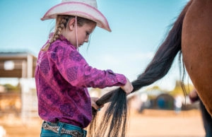 Girl braiding horse's tail